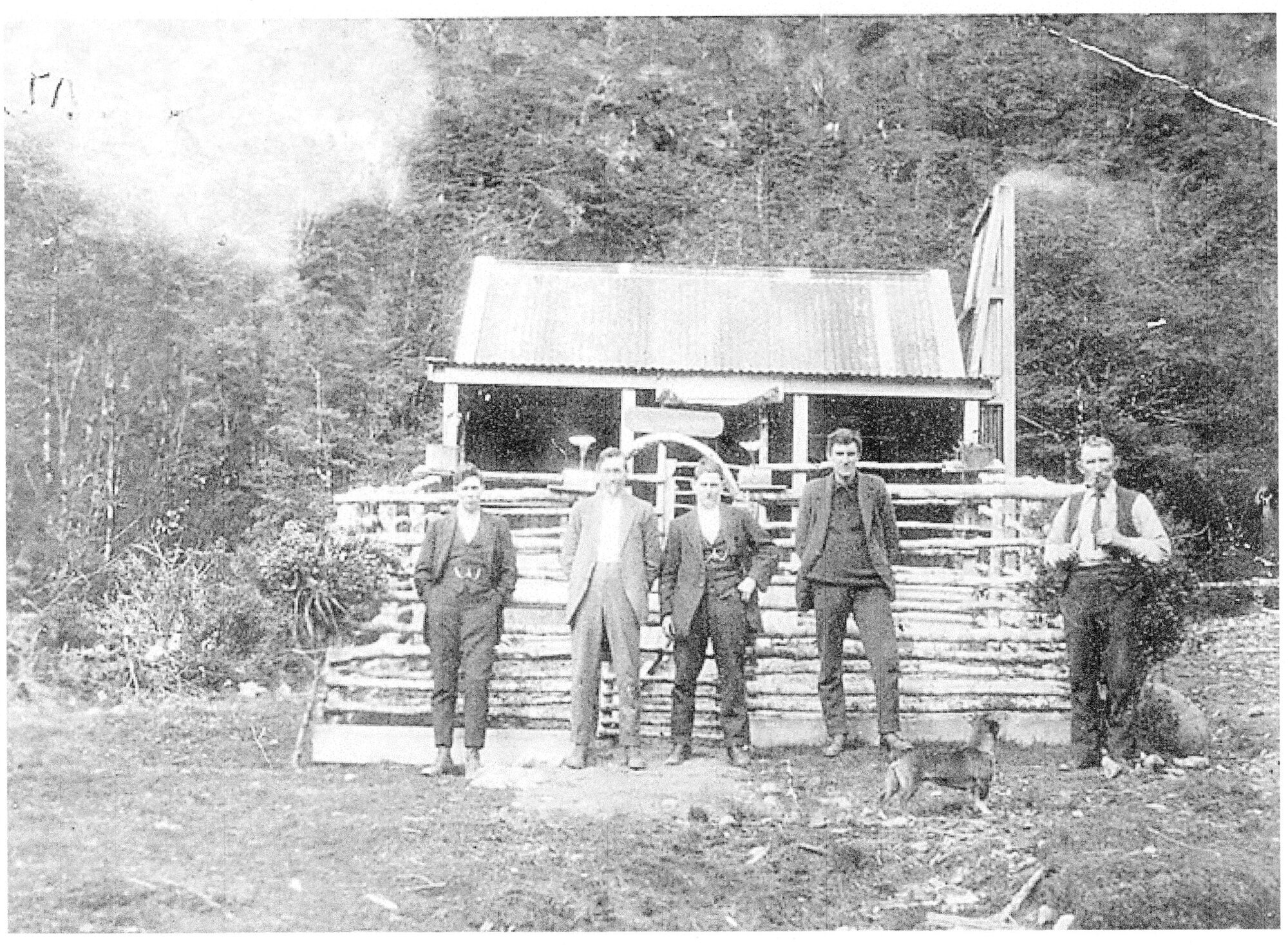 Group of men standing in front of a fenced building