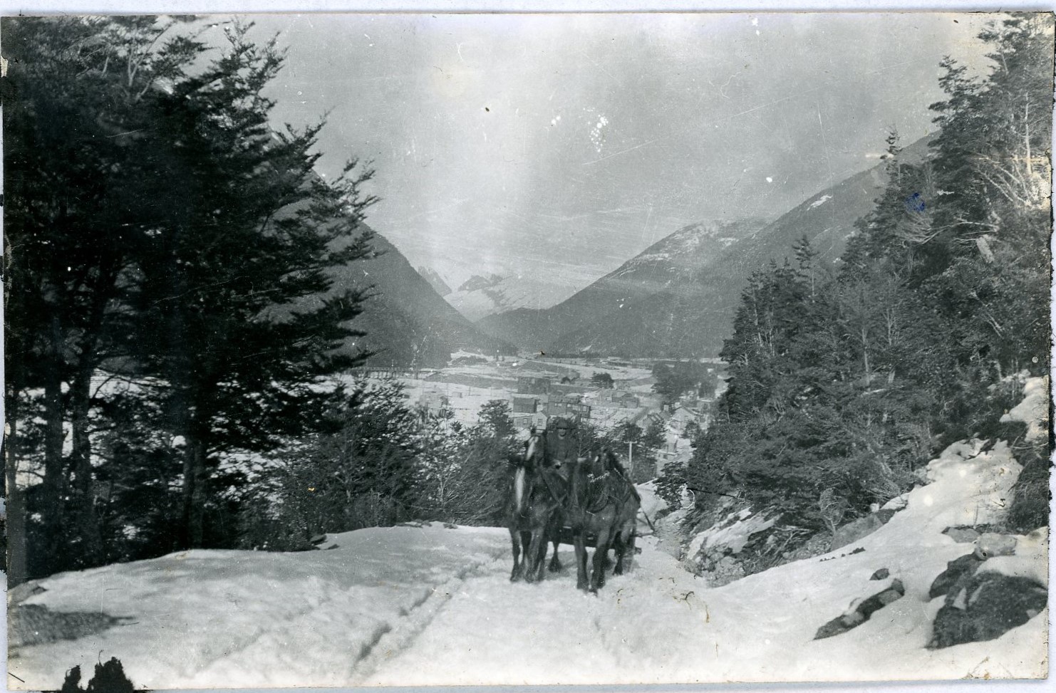 Horses hauling a load in the snow above worker's village