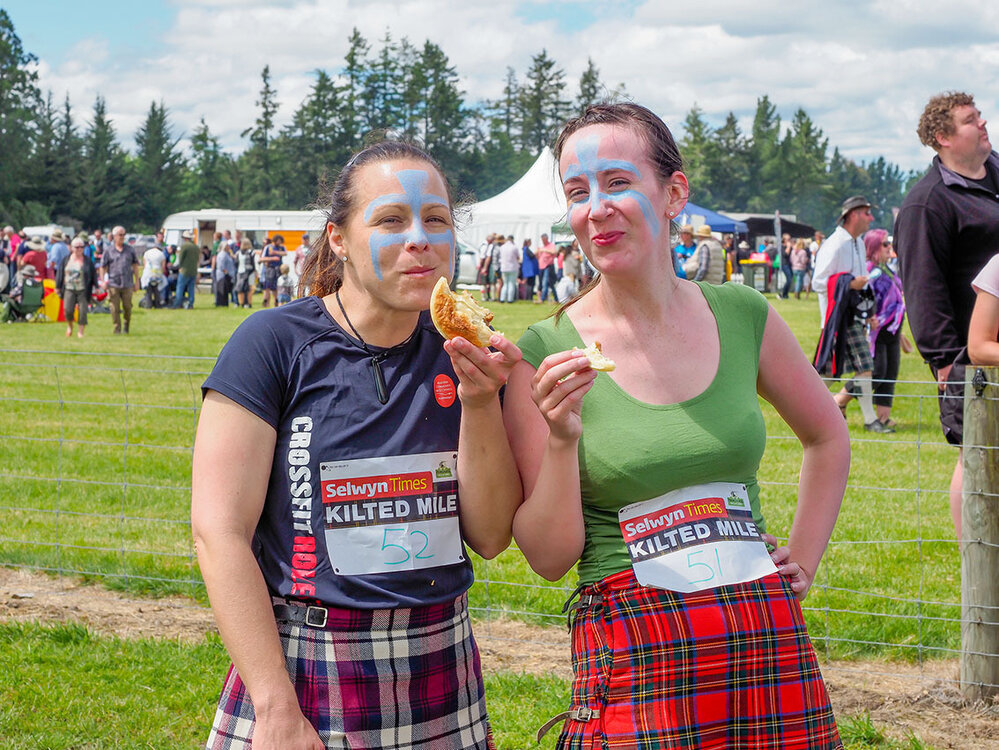 Two women eating Hororāta Pies at the Highland Games