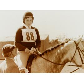 Young rider on horse speaking to judge at competition 
