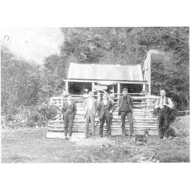 Group of men standing in front of a fenced building