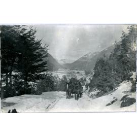 Horses hauling a load in the snow above worker's village