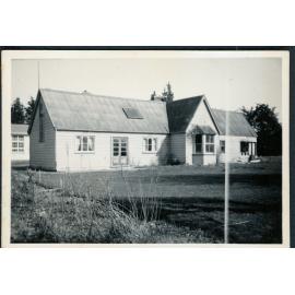 Old Courtenay School building with new school building in the background, 1956